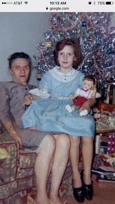 an old photo of a man and woman sitting in front of a christmas tree holding dolls