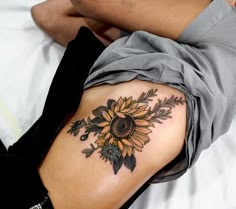 a person laying on top of a bed with a sunflower tattoo on their back