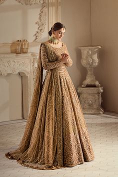 a woman in a gold gown standing next to a fireplace