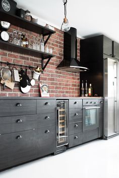 a kitchen with brick walls and stainless steel appliances in the center, along with open shelving