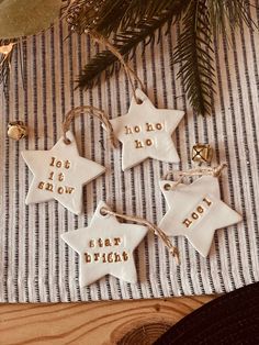 three white ceramic stars with words on them sitting next to a christmas tree ornament