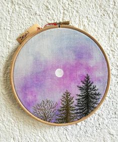 a purple and blue sky with trees in the foreground is framed by a wooden hoop