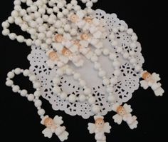 small white beads with tiny wooden dolls on them are arranged in the shape of an angel