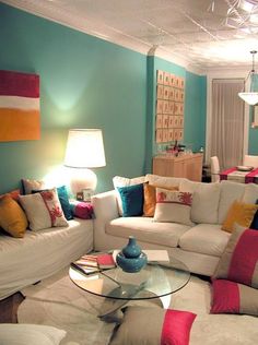 a living room filled with white furniture and colorful pillows