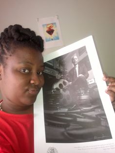 a woman holding up a black and white photo in front of her face with an afro hairstyle