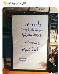 a white board with writing on it in an arabic language and some office supplies next to it