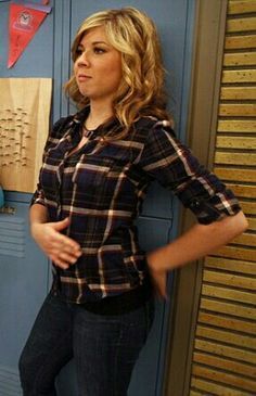 a woman standing in front of lockers holding her hand on her hip and looking at the camera