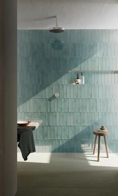 a bathroom with blue tiles on the wall and wooden stools in front of it