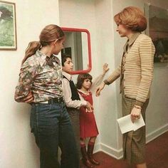 two women standing next to each other in front of a wall with pictures on it