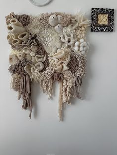 a wall hanging made out of fabric and other things on it's side, with a clock in the background