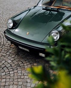 a green sports car parked on a cobblestone street