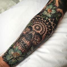 a man's arm with flowers and a skull tattooed on the left side of his arm