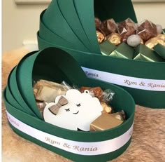 two green boxes filled with assorted chocolates on top of a brown fur surface