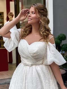 a woman in a white dress is posing for the camera with her hand on her head