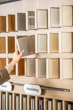 a person is holding an open book in front of a display of different types of tile