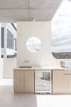 a modern kitchen with white walls and wooden cabinetry on the outside, looking out onto an ocean