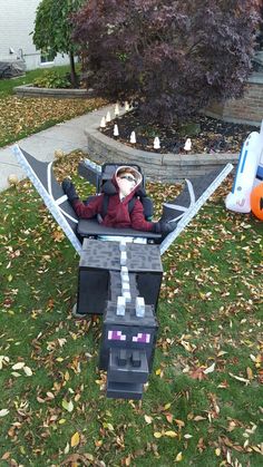 a small child in a toy airplane made out of lego blocks sitting on the grass