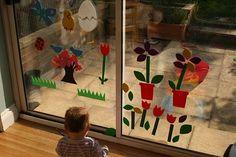 a little boy looking out the window at some flowers and birds on display in front of him