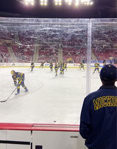 hockey players playing on an ice rink in front of the scoreboard at a stadium