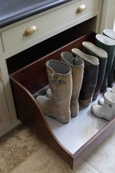 several pairs of boots are sitting in a shoe rack on the floor next to a counter