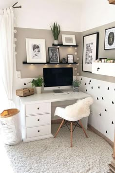 a white desk topped with a computer monitor next to a wall mounted shelf filled with pictures