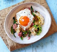 an egg is sitting on top of some food in a bowl next to a fork