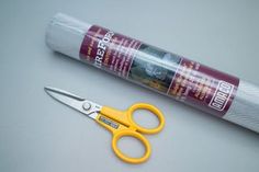 a pair of yellow scissors sitting next to a tube of glue