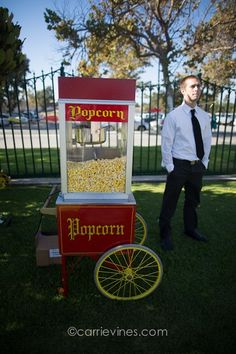 a man standing next to a popcorn cart