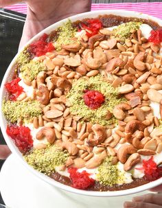 a person holding a large bowl of food with almonds and cranberries on top