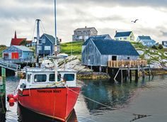 a red and white boat is docked in the water next to some houses on stilts