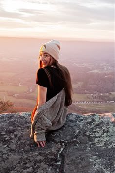 a young woman sitting on top of a rock