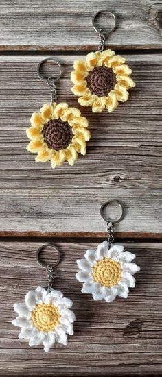 two sunflowers are hanging from key chains on a wooden surface, one is yellow and the other is white