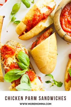 chicken parm sandwiches with tomato sauce and basil leaves on the side, sitting on a white plate