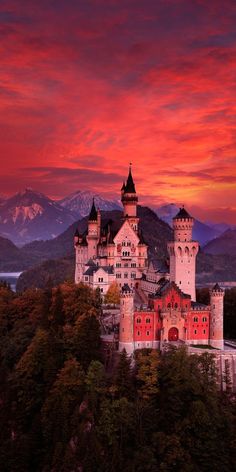 a castle with mountains in the background at sunset