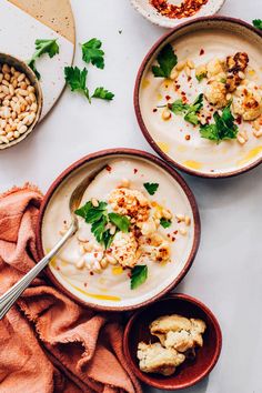 three bowls filled with different types of food and garnished with herbs on top