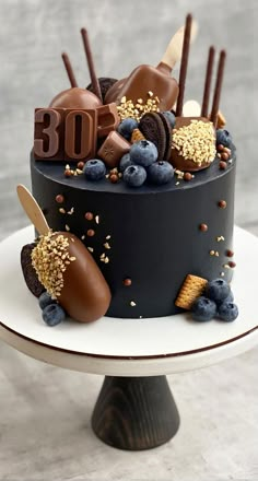 a chocolate cake decorated with blueberries, raspberries and gold sprinkles