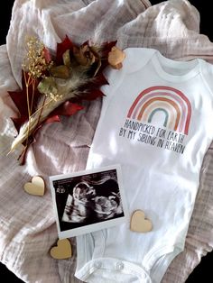 a baby's bodysuit with an image of a rainbow on it and some leaves