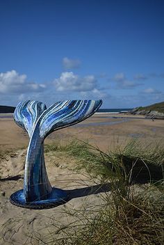 a sculpture on the beach that looks like a whale's tail