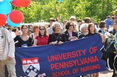 a group of people standing around each other holding a blue and red banner that reads university of pennsylvania school of nursing