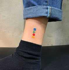 a person's foot with a small colorful dot tattoo on the left side of their ankle