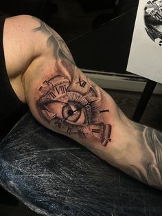 a man's arm with a clock and an eye tattoo on his left leg