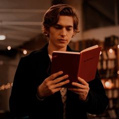 a young man reading a book in a library