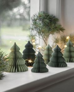 small green christmas trees sitting on top of a window sill