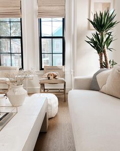 a living room filled with white furniture and windows covered in shades of light colored blinds