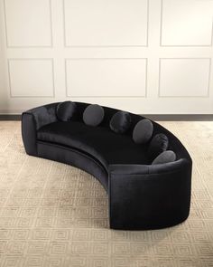 a black curved couch sitting on top of a rug