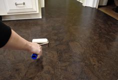 a person holding a blue and white toothbrush in their hand on the floor next to a kitchen counter