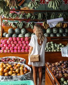 a woman standing in front of a fruit stand