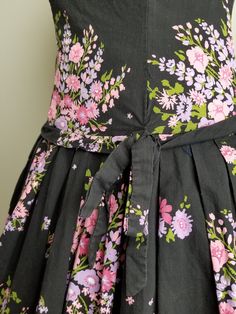 "Gorgeous 1950's dress with extremely full, pleated skirt and dropped waist. The bodice has a high neckline.The fabric is a black based floral cotton with pink and purple flowers. This dress is handmade and it is fairly obvious. There have been mends, and there may need to be a few more. There is a popped seam (quick, easy fix). Note: dress displayed with crinoline. Condition: Good vintage condition. Needs a repair of a seam or two (see photo). The handmade nature, means things aren't perfect, b Pink Floral Sundress, 1950's Dress, Dress Display, Dress And Jacket Set, Cotton Sundress, Pink And Purple Flowers, Henderson Nv, Antique Clothing, Floral Sundress