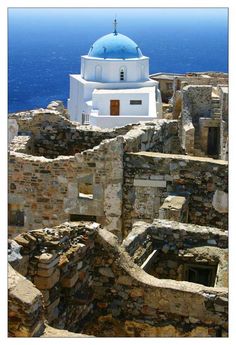 an old stone building with a blue dome on top in front of the ocean,