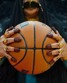 a woman holding a basketball in her hands with gold rings on it's fingers